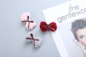 Detailed close-up of fluffy velvet hair clips in pink, dark red, and grey plush fabric