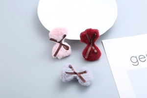 Close-up of soft plush bow hair clips in pink, burgundy, and grey colors with silk ribbon