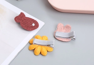 Detalle de pinzas de pelo tejidas a mano con pez, girasol y conejo para niñas