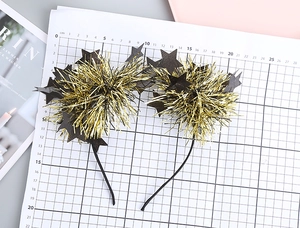 Detail of glittery star headband for festivals featuring gold pom poms and black stars