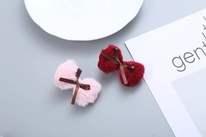 Detailed view of pink and dark red plush bow hair clips on a minimalist background