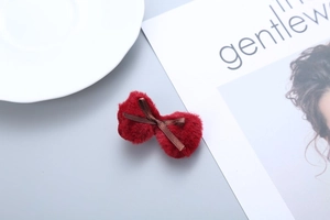 Detailed close-up of a red plush bow hair clip with a dark brown ribbon center accent