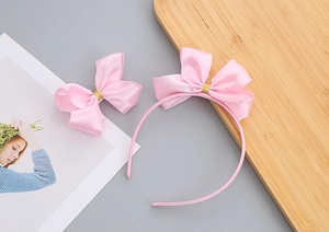 Dettaglio del set cerchietto e fermaglio con fiocco in raso rosa per bambine