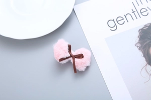 Close-up of a soft pink plush bow hair clip with a brown ribbon detail for girls