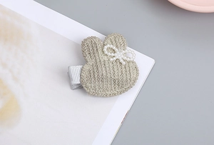 Detalle de pinza para el pelo de conejo beige tejida a mano con lazo de perlas y raso