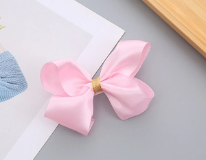 Dettaglio di fiocco in raso rosa con centro glitterato dorato per capelli bambina