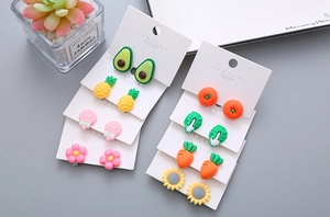 Flat lay of colorful resin vegetable and flower clip-on earrings for little girls