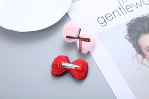 Detail of red and pink plush bow hair clips with metal duckbill clip backings
