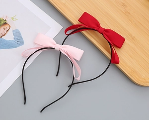 Detailed view of red and pink ribbon bow headbands on a decorative wooden tray