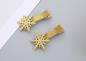 Close-up of two golden glitter snowflake hair clips with silver metal duckbill base