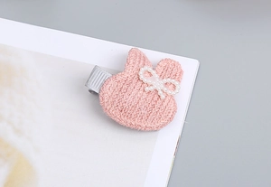 Detalle de horquilla de conejo tejida en rosa con un lazo de perlas blancas para niñas