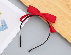 Detailed view of a sweet red fabric bow hairband on a minimalist black frame for girls