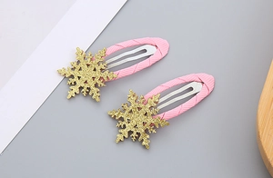 Close-up of a pair of pink snowflake hair clips with glittery golden festive accents