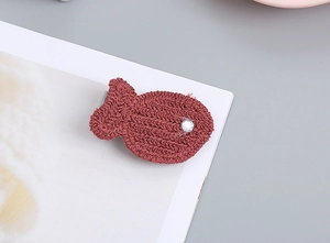 Detalle de una pinza para el pelo tejida en forma de pez marrón rojizo con strass brillante
