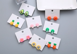 Close-up of cute resin vegetable and fruit clip-on earrings set on a white card display