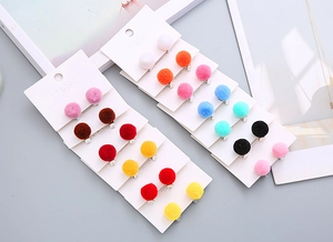 Detail view of colorful faux fur ball clip-on earrings displayed on jewelry cards