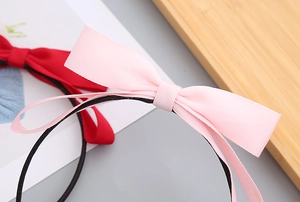 Close-up of red and pink fabric bow headbands for girls on a wooden decorative tray