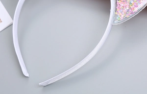 Close-up of children's cat ear headband with colorful star sequins inside transparent PVC
