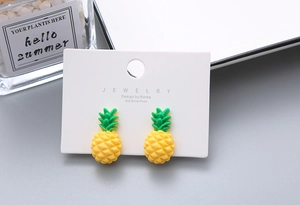 Close-up of cute yellow resin pineapple clip-on earrings for girls on white card
