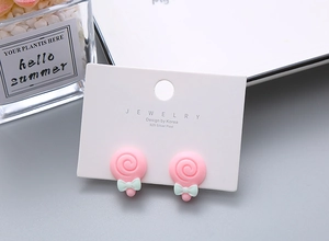 Close-up of pink lollipop earrings with mint green bows on a 925 silver needle card