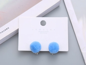 Detail shot of cute blue fluffy ball clip-on earrings for kids on display card