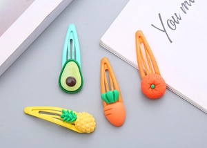 Dettaglio di fermagli per capelli color caramella con motivi carini di avocado e ananas