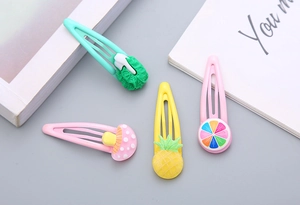 Dettaglio di quattro fermagli per capelli colorati in resina per bambine con frutta