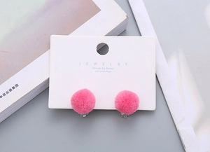 Detail of pink faux fur ball clip-on earrings with 925 silver posts on jewelry card