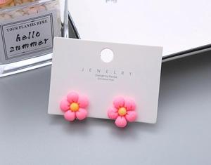Detail of pink daisy earrings with 925 silver posts on a white jewelry card