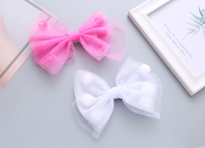 Dettaglio dei fiocchi per capelli in tulle con pon-pon nei colori rosa e bianco