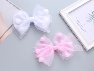 Dettaglio di fermagli in tulle rosa e bianco con morbidi pompon all'interno per ragazze