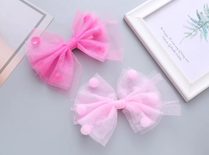 Dettaglio dei fermagli per capelli a fiocco in tulle rosa con pompon per bambine