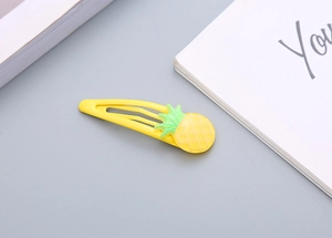 Dettaglio di un simpatico fermaglio per capelli a forma di ananas giallo per bambine