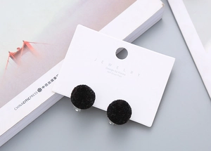 Detail of soft black fuzzy pom pom earrings on white card with 925 silver needle post