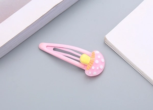 Dettaglio del fermaglio per capelli in metallo rosa con decoro fungo in resina per bambine