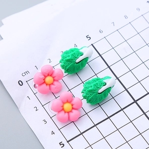 Cute resin flower and vegetable ear clips for girls on a measurement grid scale