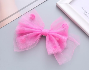 Dettaglio del fiocco rosa in rete con pompon di peluche e fermaglio in metallo