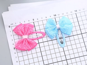 Detail showing 5cm pink and blue handmade lace ribbon bow hair clips on measuring grid