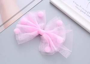 Dettaglio del fiocco rosa in tulle con pompon soffici e strati di rete delicata