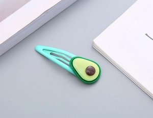 Dettaglio di un fermaglio per capelli BB in metallo verde menta con charm avocado in resina