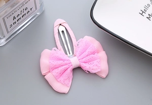 Detail of pink lace ribbon bow hair clip showing textured fabric and BB clip mechanism