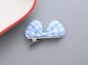 Dettaglio di un fermaglio per capelli a fiocco a quadretti blu e bianchi con clip in metallo