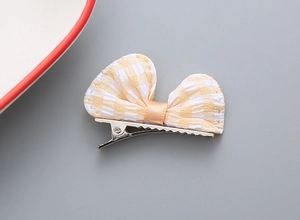 Dettaglio del fiocco per capelli a quadretti gialli con clip a coccodrillo per bambine