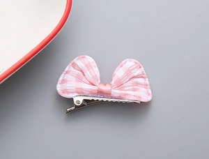 Dettaglio della molletta per capelli con fiocco a quadretti rosa e clip in metallo