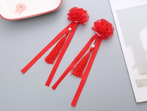 Detail view of red flower hair clips with long tassels and ribbons for girls