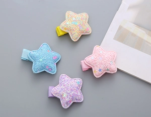 Close-up of four macaron-colored sequin star hair clips with glitter fabric and metal duckbill grips