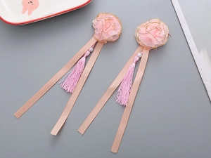 Detailed close-up of pink organza flower hair clips with silk tassels and pearl accents