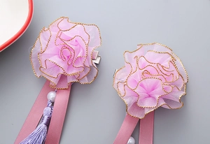 Detail of girls' floral hair clips with purple silk tassels and faux pearls