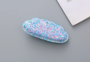 Macro shot of sequined cloud-shaped hair clip with shimmering pink and blue glitter finish
