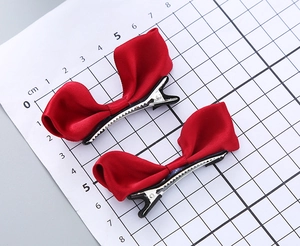 Détail des nœuds à cheveux en satin rouge de 5,5cm sur un fond de mesure gradué